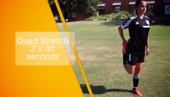 young girl soccer player stretching quads on grass field